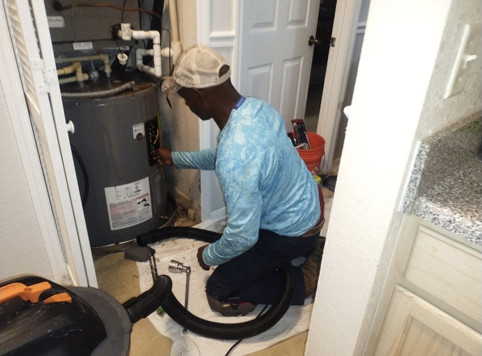 Technician servicing an electric water heater inside a home